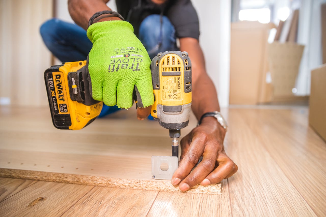 about-us-01 Man using a power drill for home improvement on a wooden floor with precision.