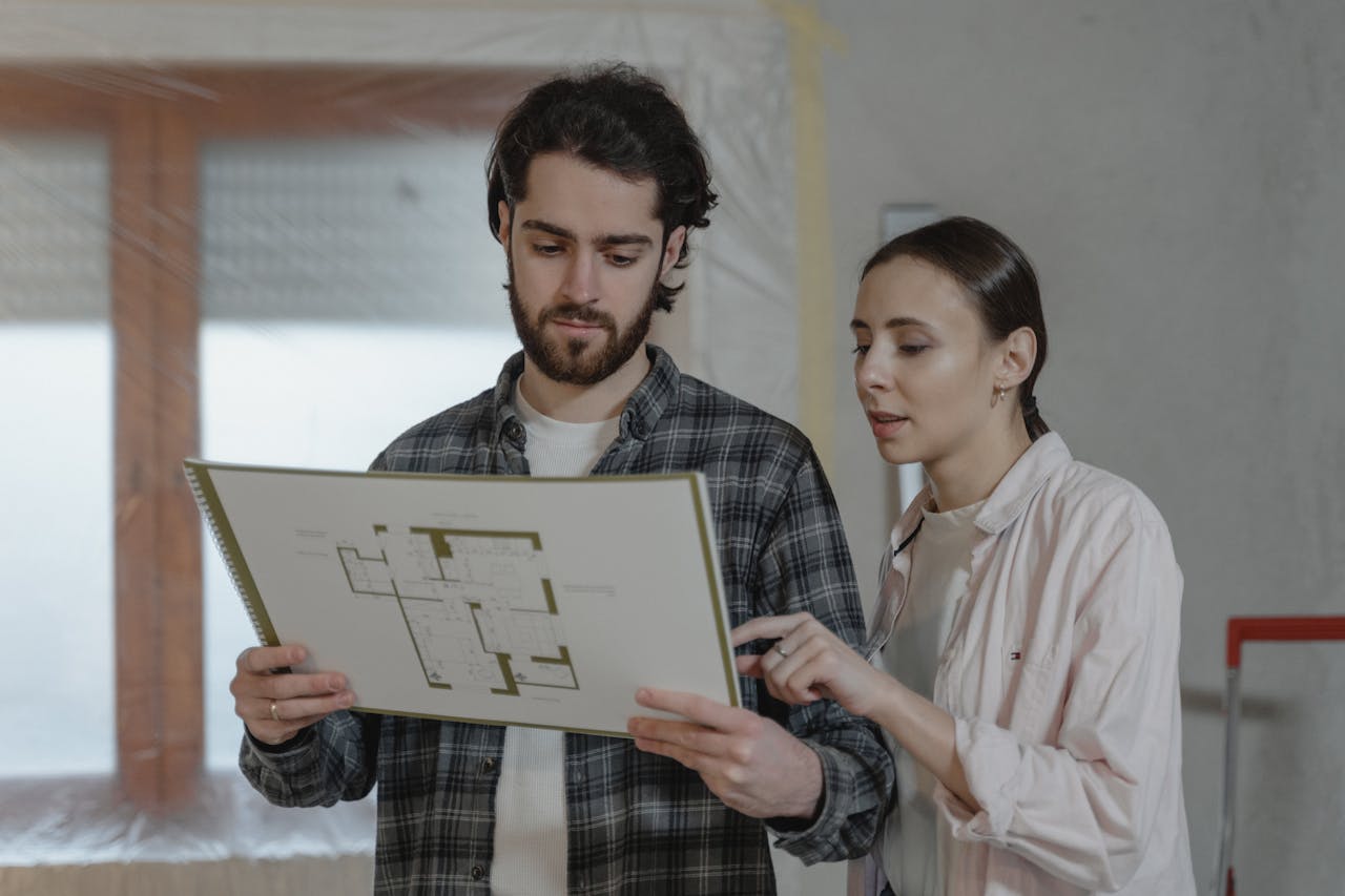 services-04 A man and woman examining a floor plan for home improvement indoors.